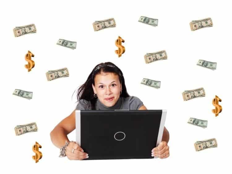 A girl holding laptop and money in background