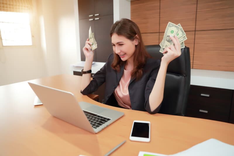 Successful working women with exciting face and banknotes on her hand