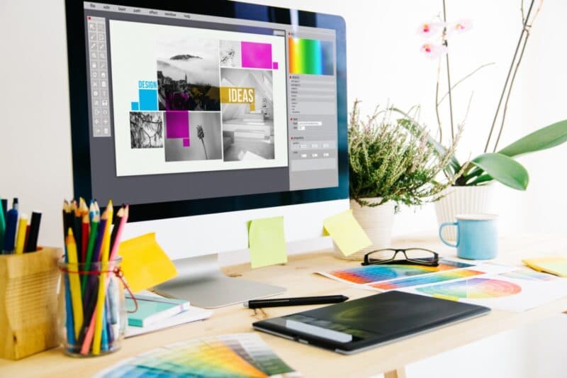 Freelance graphic design workspace with a computer screen on the desk showing graphic design work