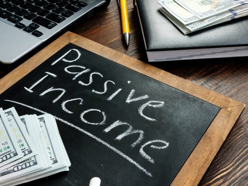 Board displaying "Passive Income" alongside a stack of cash, symbolizing financial growth and revenue generation