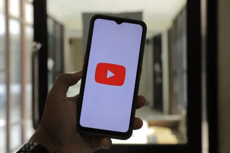 Person Holding a Black Cellphone with Youtube Logo