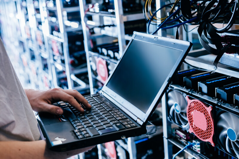 Man holding a laptop while in a Cryptocurrency mining farm 