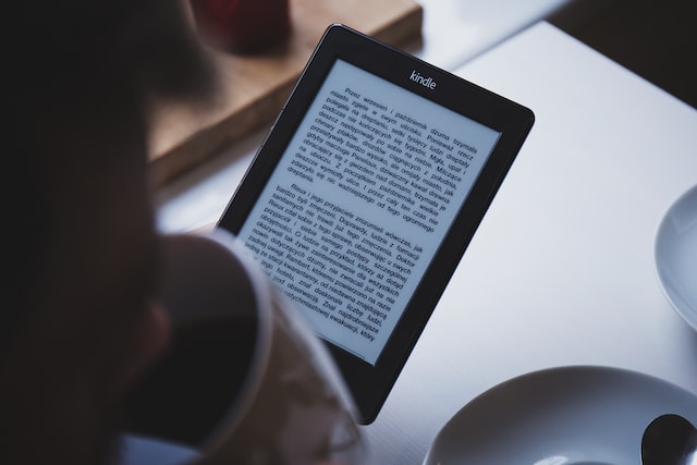 Someone using an ebook reader with a coffee cup in hand