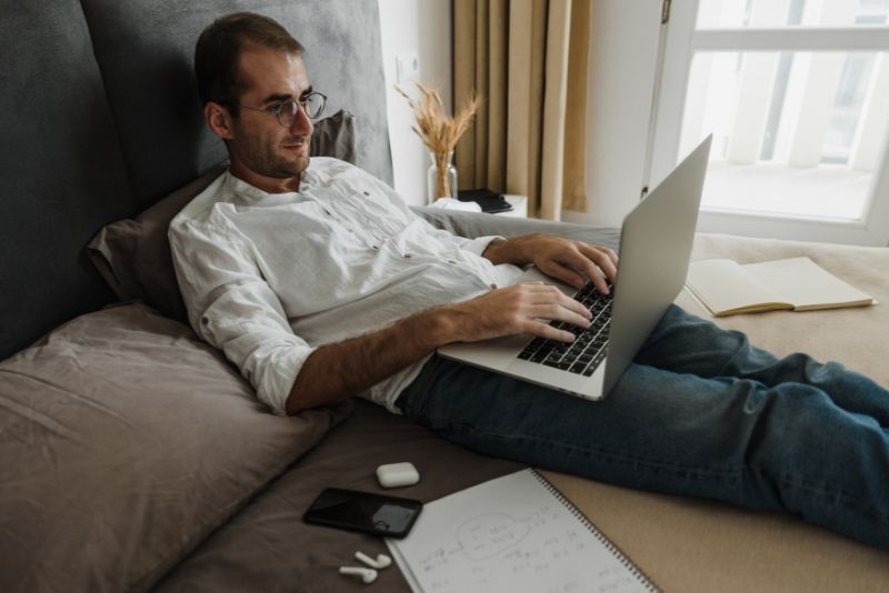 A Man On A Bed With His Laptop