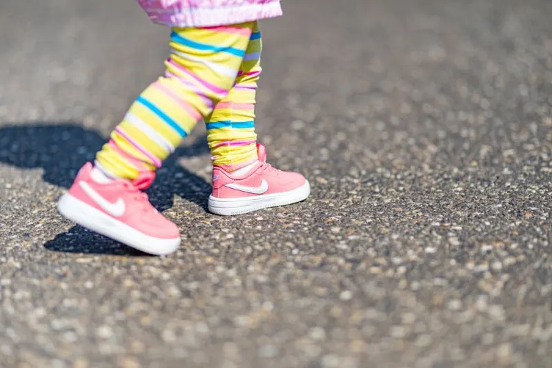 Cute Little Girl Legs With Nike Pink Sport Shoes And Rainbow Pants