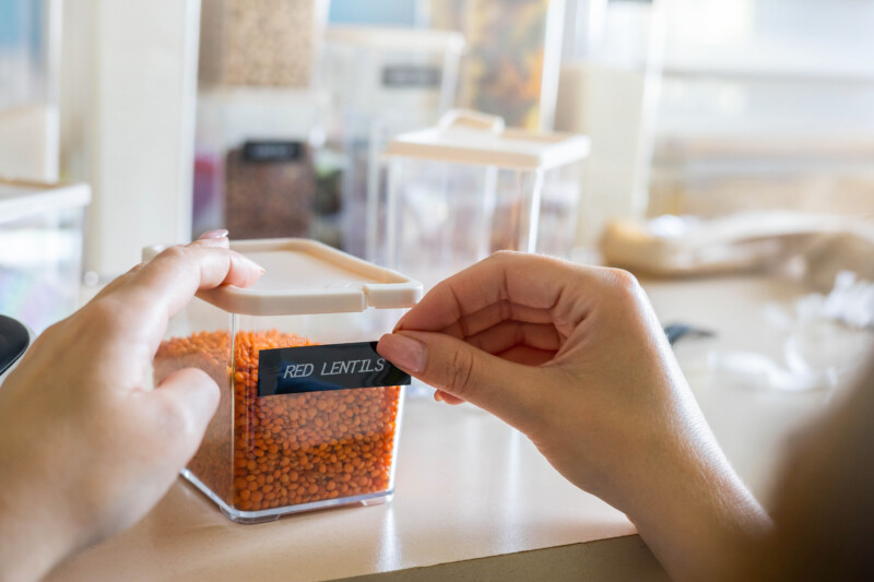 Closeup female hands applying printing sticker with name red lentils on transparent plastic case box
