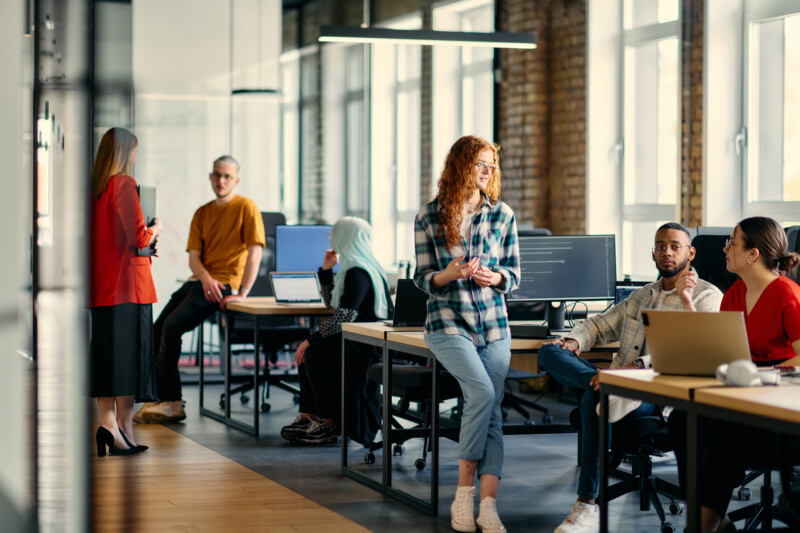 A diverse group of young business individuals congregates in a modern startup coworking center, embodying collaborative innovation and a dynamic atmosphere